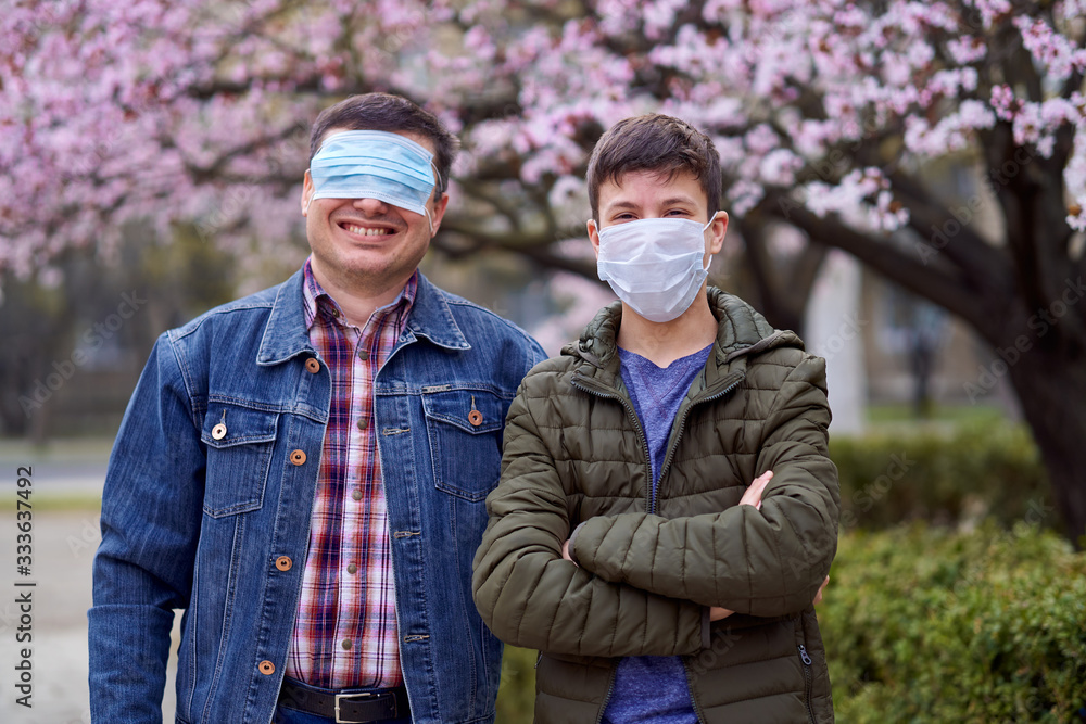 father and son with a face mask are in the city outdoor, blooming trees, spring season, flowering time - concept of allergies and health protection from dusty air father and son with a face mask are in the city outdoor, blooming trees, spring season, flowering time - concept of allergies and health protection from dusty air