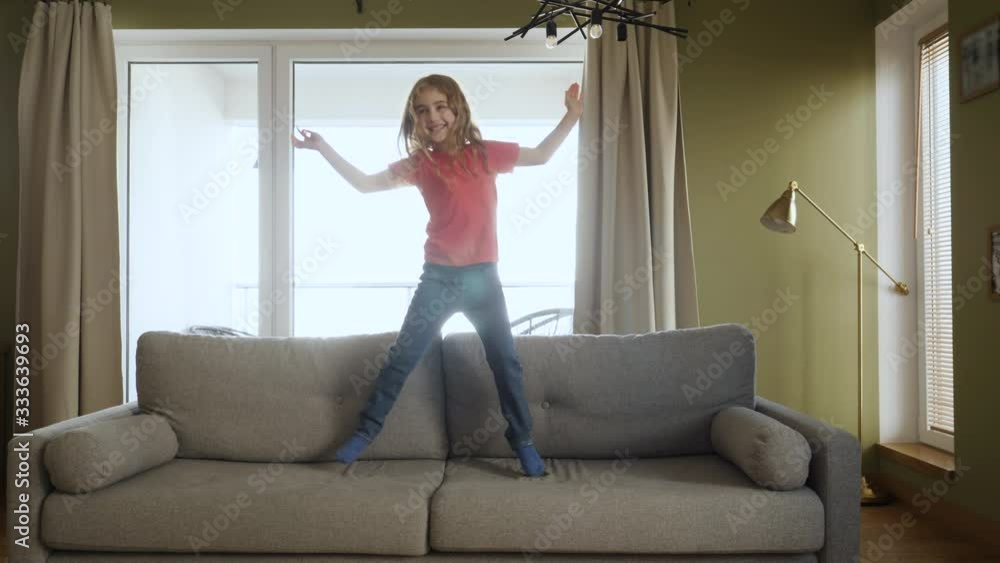 Daughter Playing in Living Room. Funny Happy Little Girl are Dancing and Jump on Couch at Home. Love Lifestyle Home. Slow Motion. Little Happy Child Girl in Casual Jumping and Dancing on Sofa. Daughter Playing in Living Room. Funny Happy Little Girl are Dancing and Jump on Couch at Home. Love Lifestyle Home. Slow Motion. Little Happy Child Girl in Casual Jumping and Dancing on Sofa.