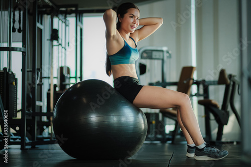 Women exercising sit-ups on exercise ball in gym