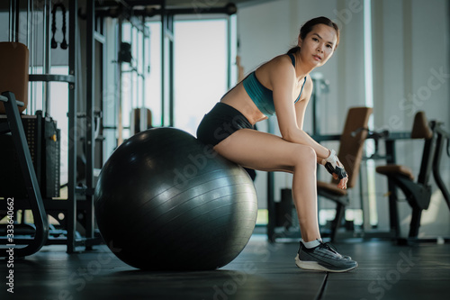 Young women sitting on ball after exercise in gym