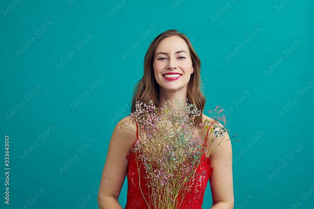 Young woman in nice red dress smiling and holding a beautiful bouquet of dryed flowers Young woman in nice red dress smiling and holding a beautiful bouquet of dryed flowers