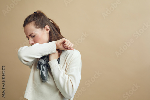 Photos Pretty woman with a scarf having the flu and coughing in the sleeve concept