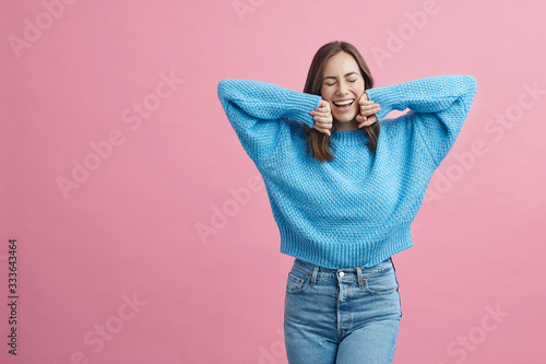 Portrait of attractive girl dancing in a blue sweater on a pink background