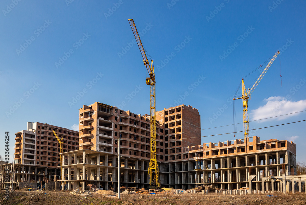 Work in progress on a new apartment block. Tall building under construction with cranes. Construction Site of New Building