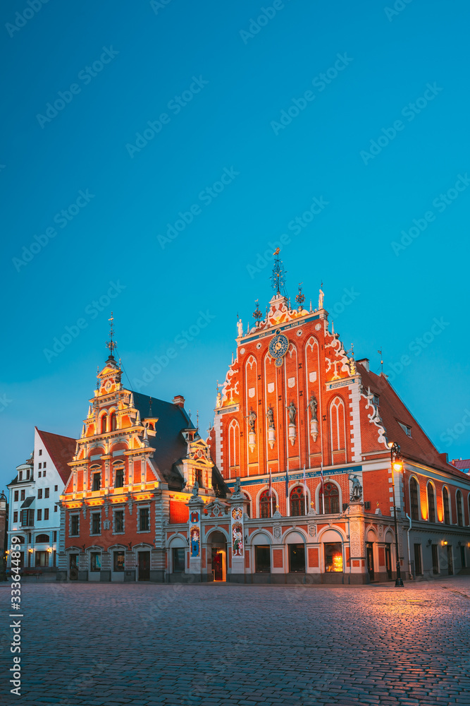 Riga, Latvia. Schwabe House And House Of The Blackheads At Town Hall Square, Ancient Historical Landmark And Popular Touristic Showplace In Summer Evening. Night Illuminations