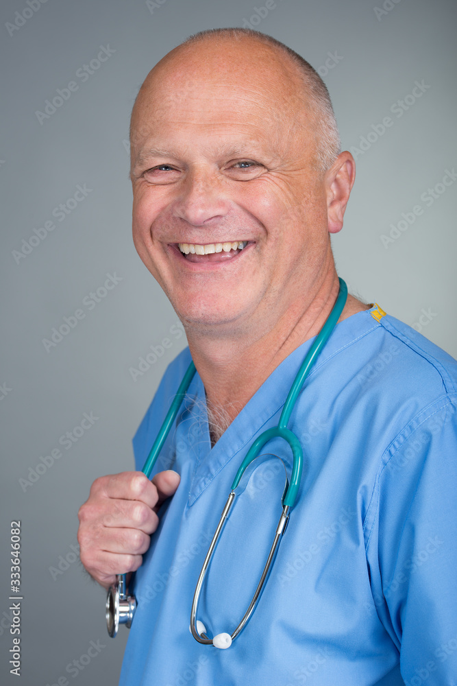 Portrait of a smiling/happy doctor, wearing blue scrubs with stethoscope, against a light background. Portrait of a smiling/happy doctor, wearing blue scrubs with stethoscope, against a light background.