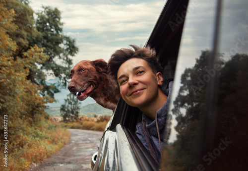 woman and dog peep out of a car window