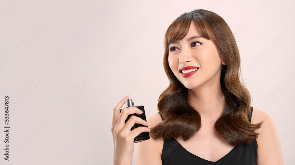Asian girl with perfume, young woman applying perfume on her wrist and smelling Asian girl with perfume, young woman applying perfume on her wrist and smelling