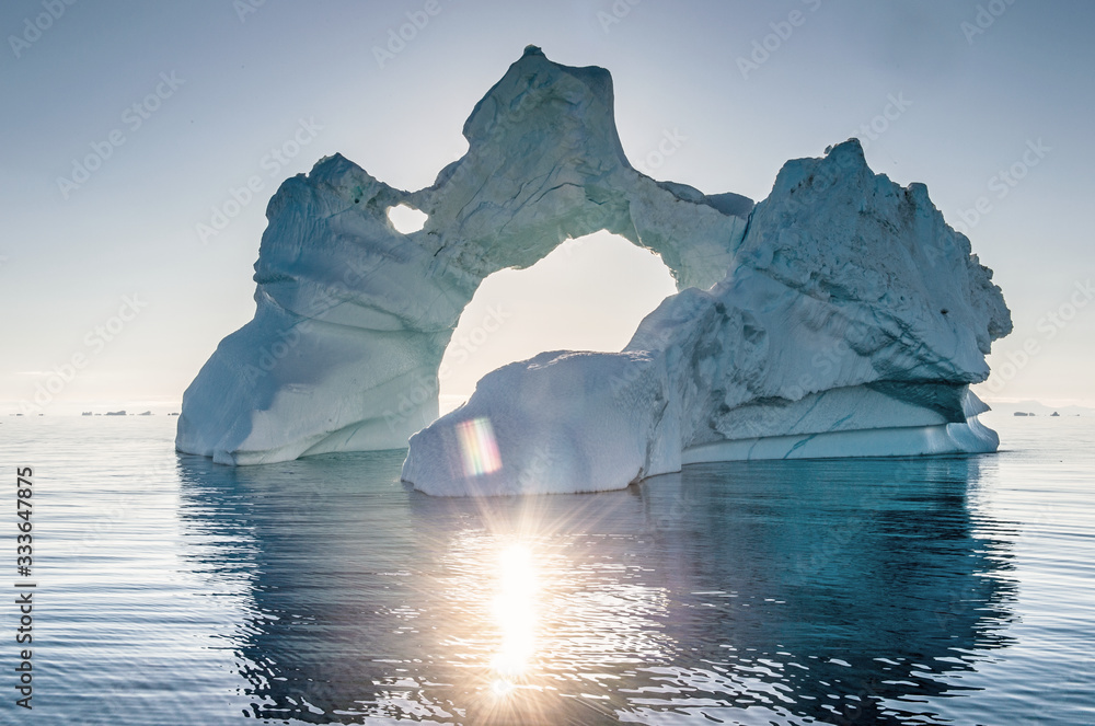 Iceberg during sunrise with backlight by sunrays. Disko Bay, Western Greenland.