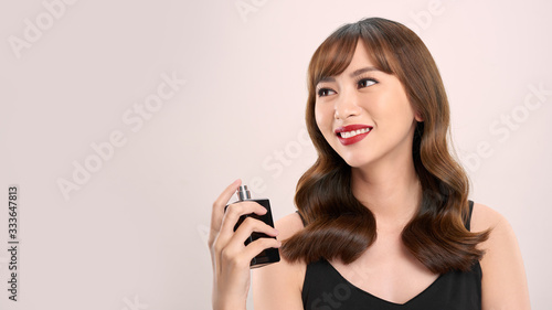 Asian girl with perfume, young woman applying perfume on her wrist and smelling