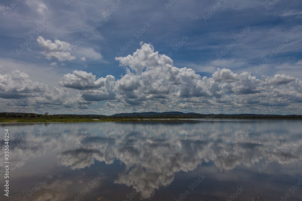 Mirror Effect on the Minneriya Wewa Lake at the Minneriya National Park , Sri Lanka. Cloudscape panorama landscape photography with reflection of the clouds on the water surface. Cumulus clouds