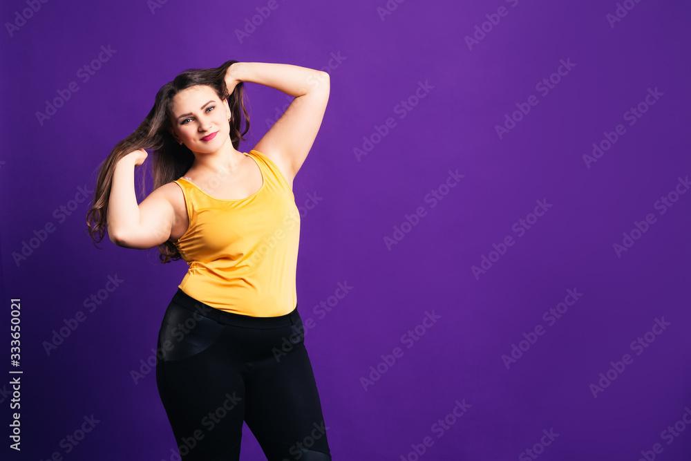 Happy plus size fashion model in casual clothes, cheerful fat woman on purple background