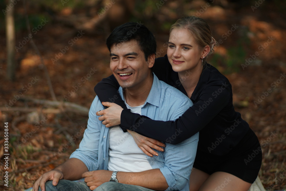Fototapeta premium European couples, men and women Showing love to each other in the garden. During the holidays, warm and comfortable holidays in the fields and large trees. Who are planning a marriage