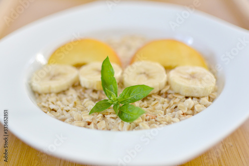 Fresh oatmeal porridge with banana, peach and honey for healthy breakfast