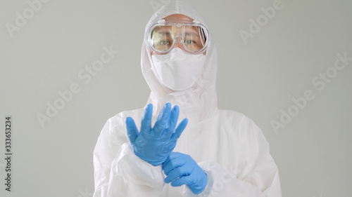 Asian doctor in protective hazmat PPE suit wearing medical latex gloves photo