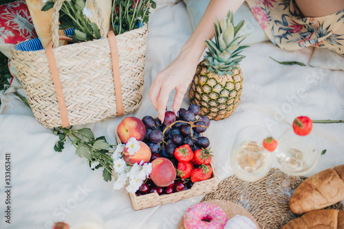Picnic at the park on the grass: tablecloth, basket, healthy food and accessories, top view