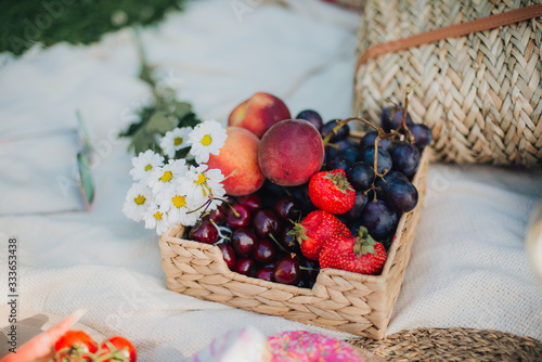 Picnic at the park on the grass: tablecloth, basket, healthy food and accessories, top view