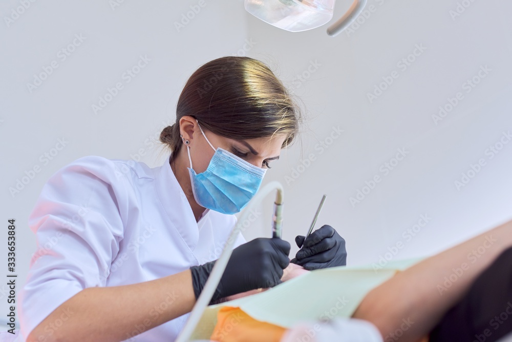 Naklejka premium Woman doctor dentist treating teeth to girl patient in dental office