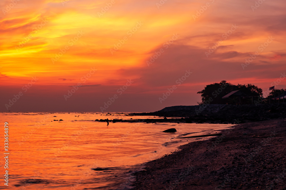 Beautiful orange sunset background on the beach. Soft wave hitting the shore