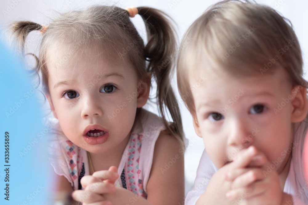 Young children lie on their stomachs and watch cartoons. Beautiful ...