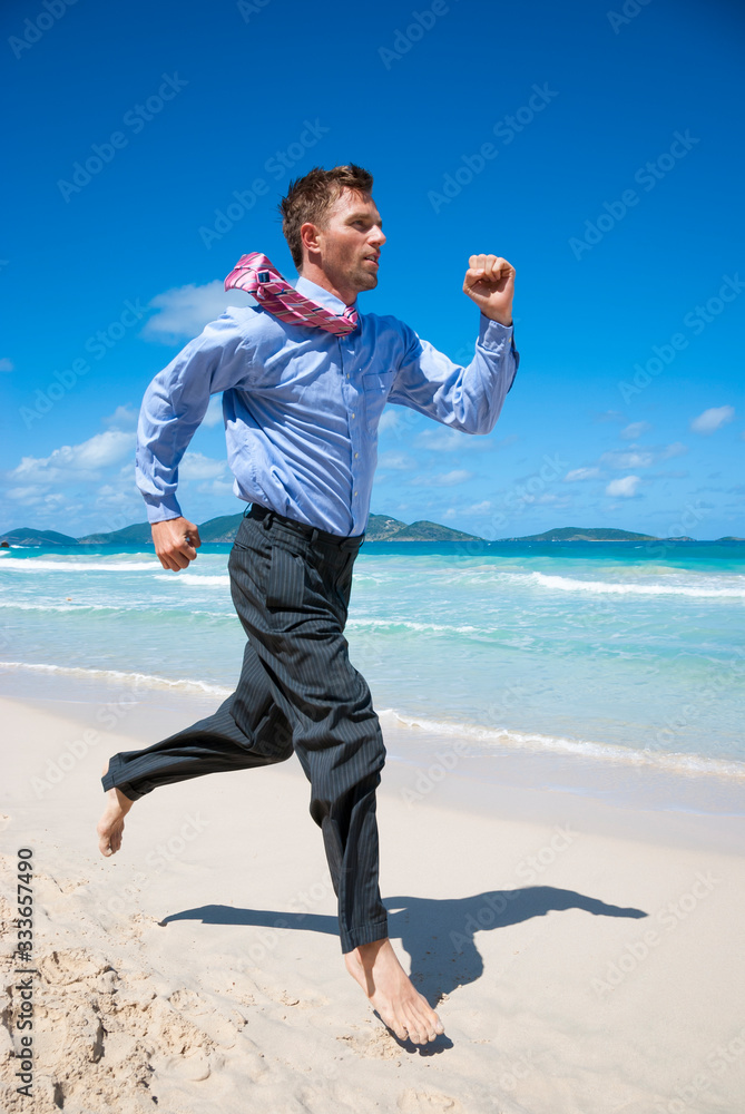 Barefoot businessman running along an empty tropical beach Barefoot businessman running along an empty tropical beach