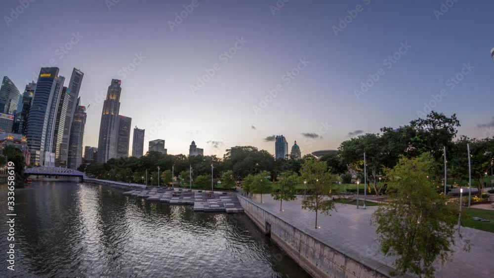 Singapore skyscrapers skyline with white Anderson Bridge and a few towers of financial district near esplanade park park day to night transition timelapse. Some green foliage on both sides. Singapore skyscrapers skyline with white Anderson Bridge and a few towers of financial district near esplanade park park day to night transition timelapse. Some green foliage on both sides.