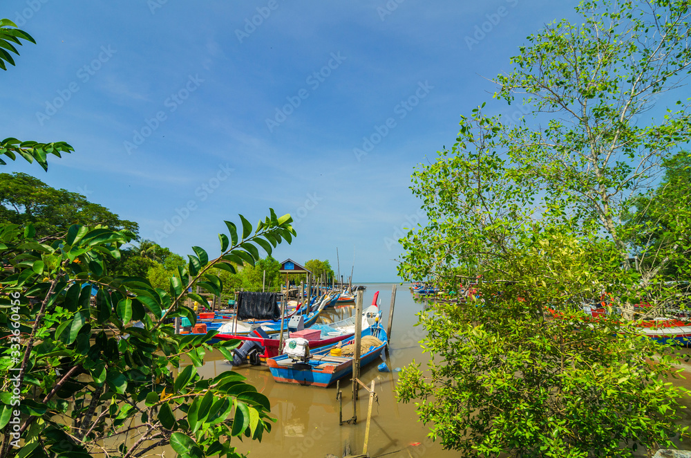 Beautiful rural scenery, fisherman boat moored near wooden jetty over blue sky background