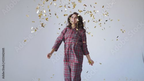 Beautiful woman dancing and throwing gold confetti.