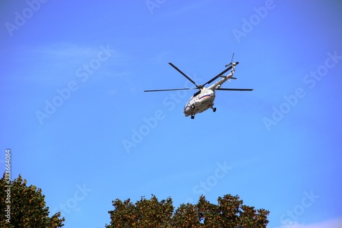 helicopter over the trees in the blue sky