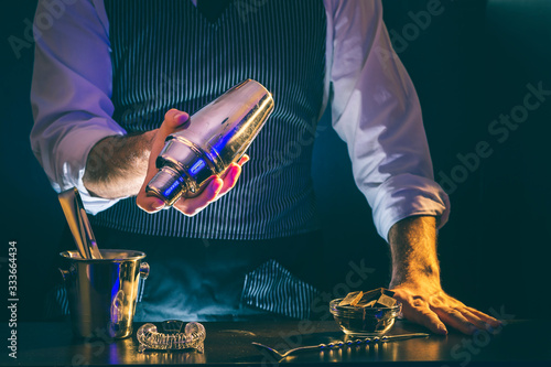 Foto Bartender making cocktail, using cocktail shaker