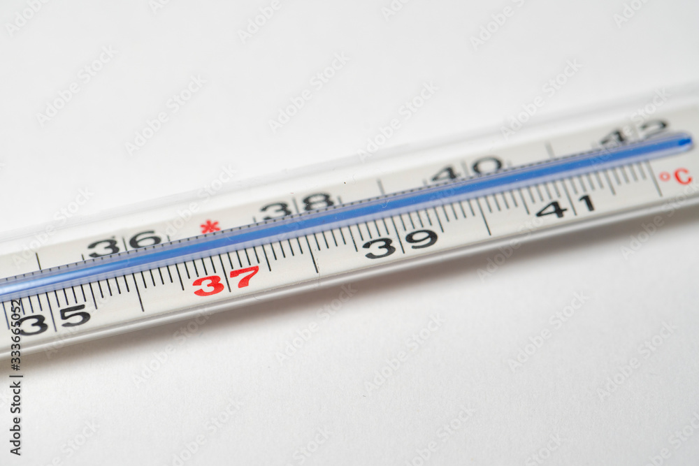 Mercury in glass thermometer on white surface. Copy space on top and bottom. Fever thermometer in analog form for measuring high temperature due to illness like flu or coronavirus Mercury in glass thermometer on white surface. Copy space on top and bottom. Fever thermometer in analog form for measuring high temperature due to illness like flu or coronavirus