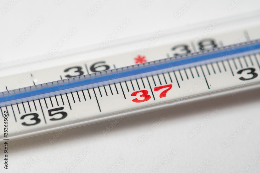 Mercury in glass thermometer on white surface. Copy space on top and bottom. Fever thermometer in analog form for measuring high temperature due to illness like flu or coronavirus Mercury in glass thermometer on white surface. Copy space on top and bottom. Fever thermometer in analog form for measuring high temperature due to illness like flu or coronavirus