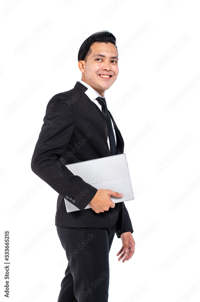 Confident young handsome businessman in black suit holding laptop and smiling while standing against white background Confident young handsome businessman in black suit holding laptop and smiling while standing against white background