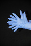 Two blue gloved hands, palms against palm, fingers offset, on black background