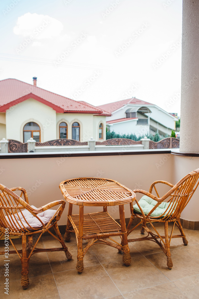 Fototapeta premium Table and two wicker chairs and the rooftop view from the outdoor terrace.