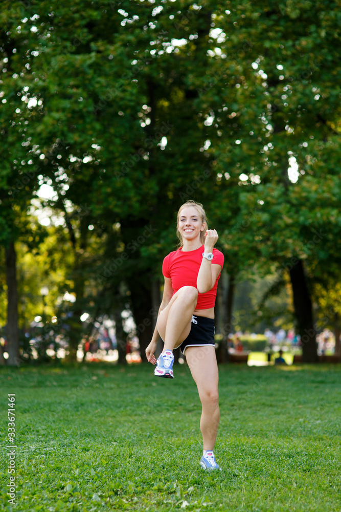 A young blonde girl is engaged in sports in the park, a woman does a warm-up in the street. Active outdoor training