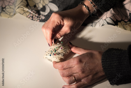 Young designer works in her workshop with colorful and flowery fabrics.