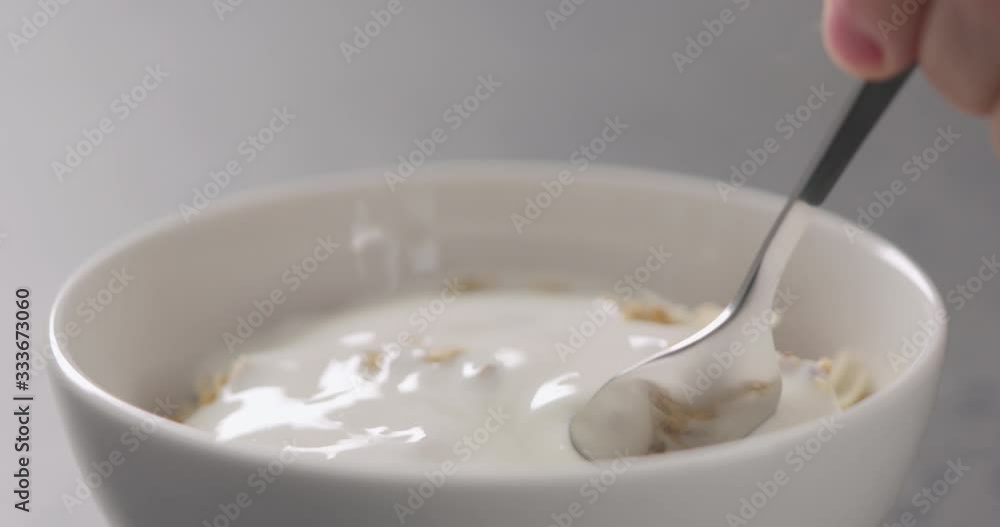 Slow motion closeup eating granola with almond flakes poured with yogurt Slow motion closeup eating granola with almond flakes poured with yogurt