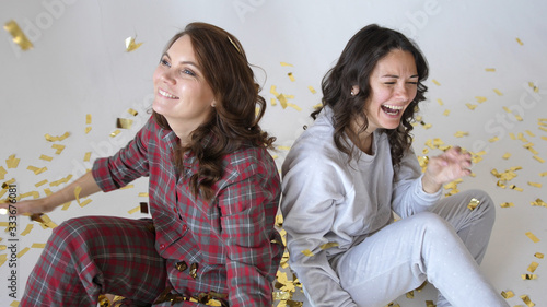 Beautiful happy women smiles through gold glitter confetti on a white background