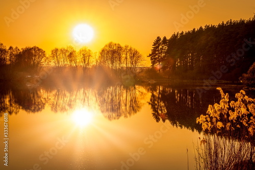 Breathtaking view of the wide angle sunset over the lake with sun reflection and orange sky © MKozloff
