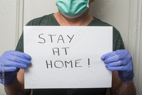 Portrait of doctor wearing medical mask to protect against the corona virus with prevention message : stay at home