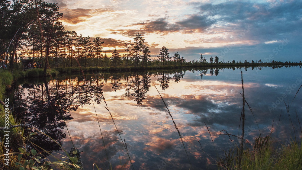 Fototapeta premium Beautiful summer sunset cloudy sky is reflecting in calm lake water. Picturesque landscape background as beauty of nature and environmental protection concept. Time lapse camera motion 4K UHD video.