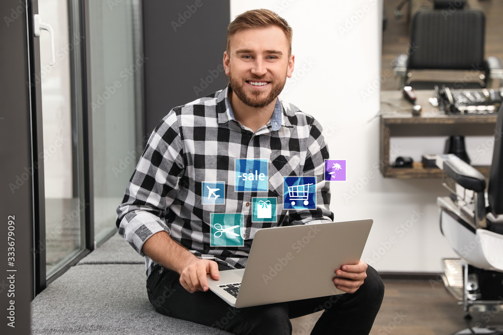 Young man using laptop in barber shop. Online shopping Young man using laptop in barber shop. Online shopping