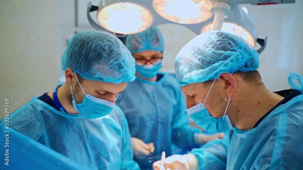 Surgical process to a patient by specialists. Doctors and assistant use medical instruments during operation in the operating room. Surgical process to a patient by specialists. Doctors and assistant use medical instruments during operation in the operating room.
