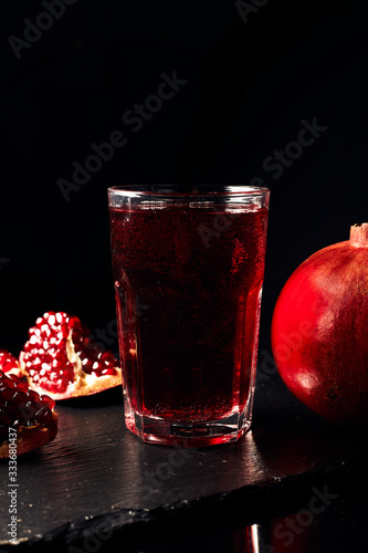 Pomegranate juice on a dark background. Pieces of pomegranate on a dark background. Summer drink.