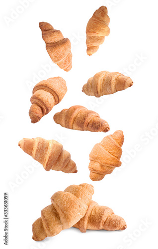 Falling delicious fresh baked croissants on white background. French pastry