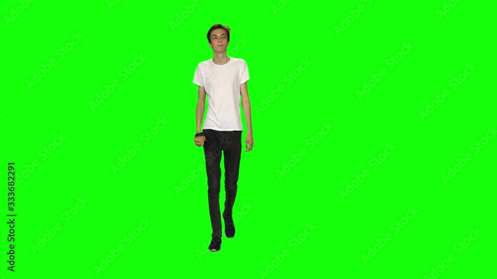 Tall skinny teen guy calmly walking and drinking coffee on green screen background. Chroma key, 4k shot. Front view. Tall skinny teen guy calmly walking and drinking coffee on green screen background. Chroma key, 4k shot. Front view.