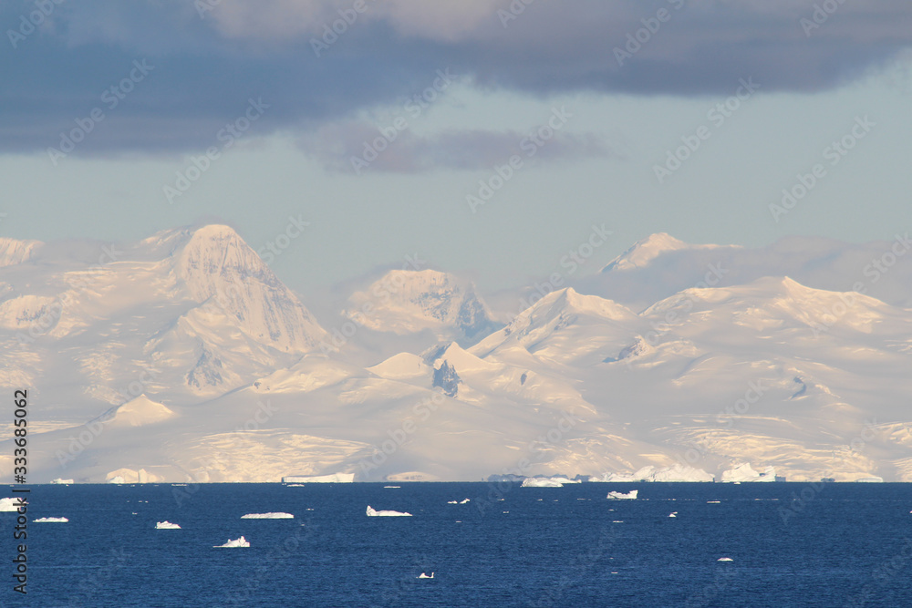 Icebergs and mountains  in the Gerlache Strait. Sunset lights in the coast of the Antarctic Peninsula, Danco Coast, Antarctica