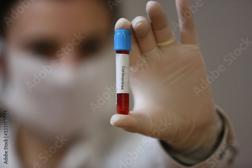 Nurse wearing respirator mask holding a positive blood test result for the new rapidly spreading Coronavirus