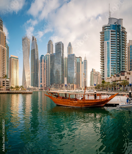 Panoramic view with modern skyscrapers and water pier of Dubai Marina at sunset, United Arab Emirates